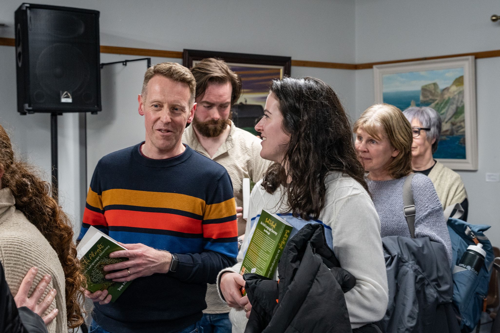 Beirt rannpháirtithe ag caint ag seoladh leabhair in Oideas Gael