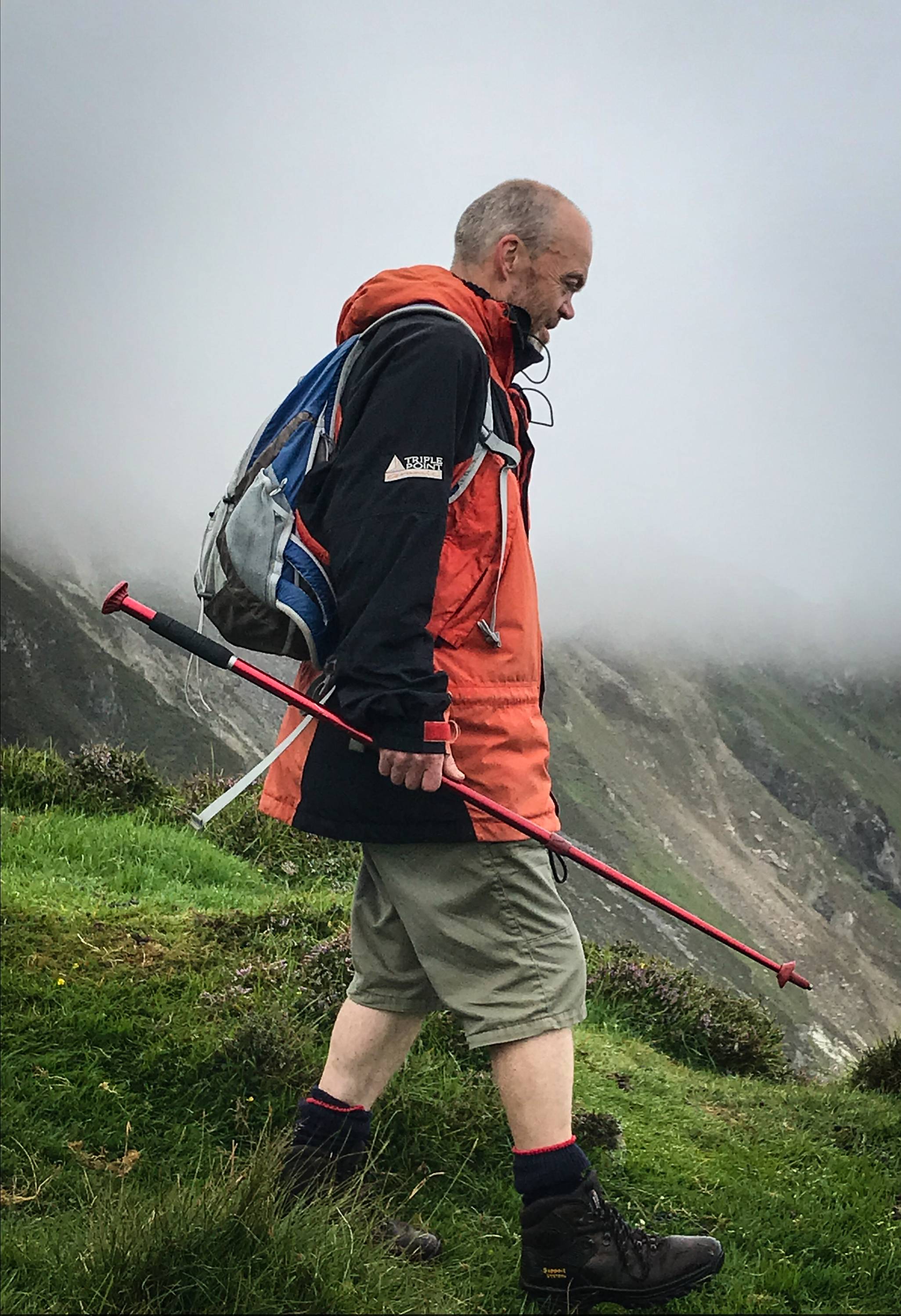 Cnocadóir os comhair sliabh atá faoi scamall