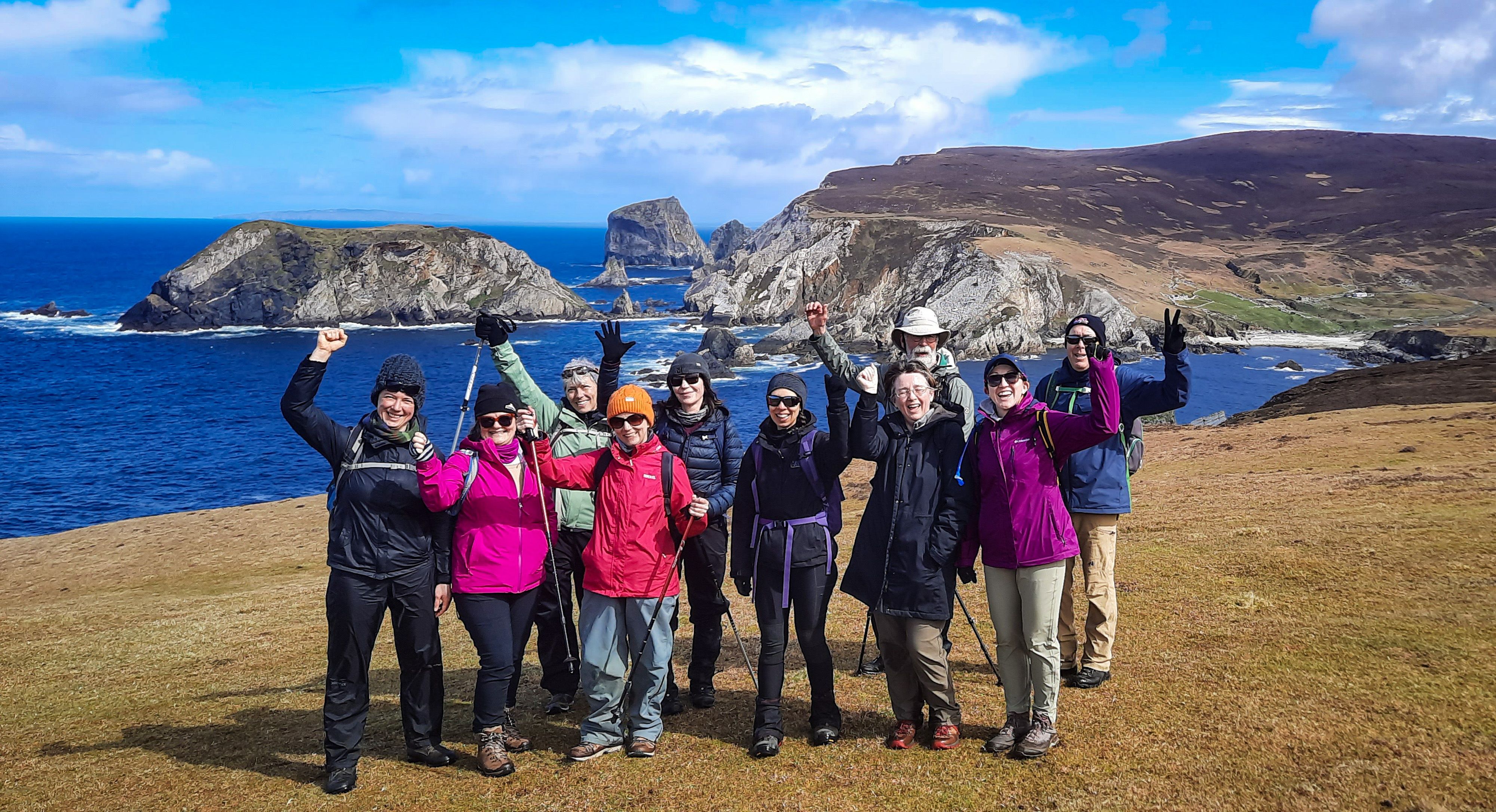 Hill walking group with arms raised; An Port in the background