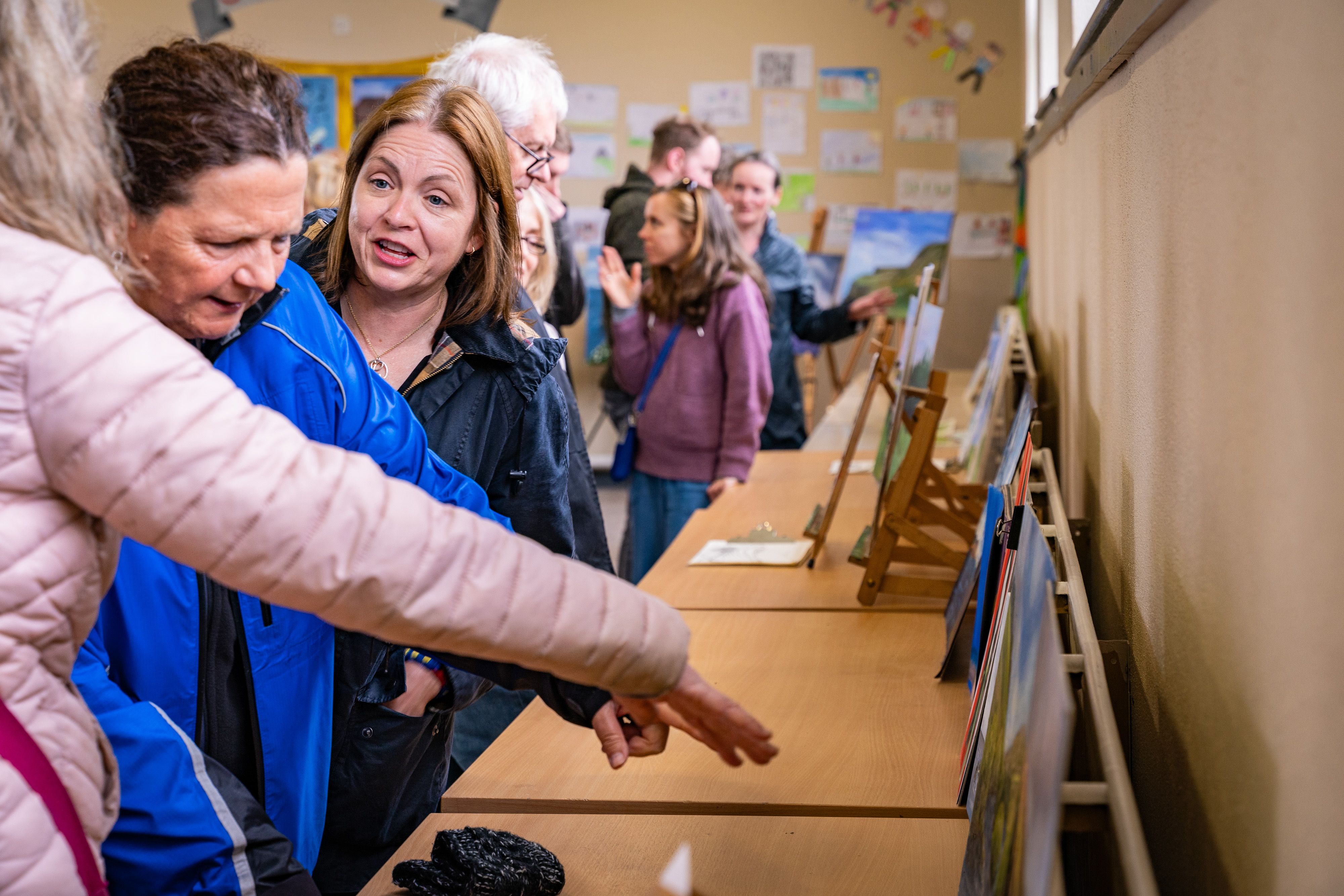 People looking at pictures on display at a painting exhibition in the local primary school
