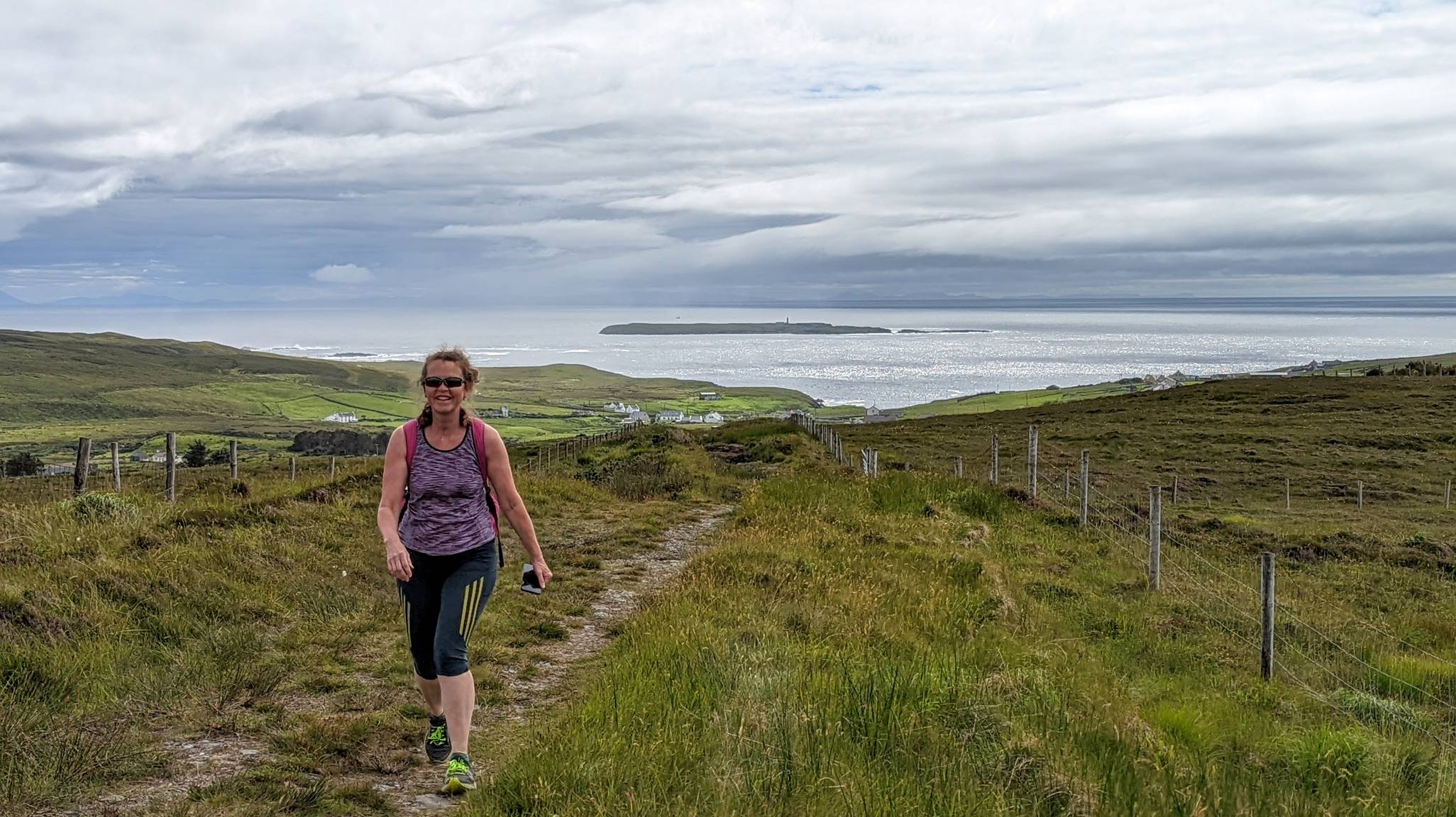 Bean ag siúl ar Mhalaidh Útha, Reachlainn Uí Bhirn sa chúlra