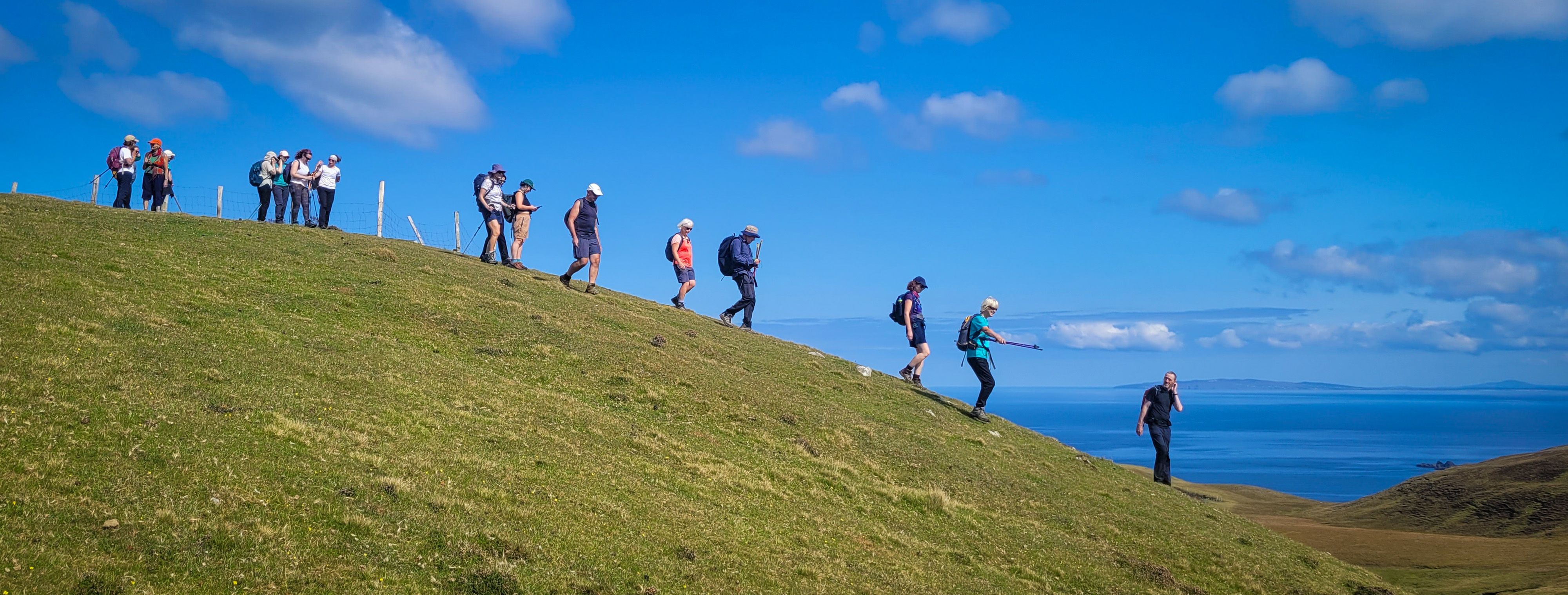 Dream Siúl Sléibhe ag siúl síos an chnoic faoi stiúir an treoraí Brendan McDyer