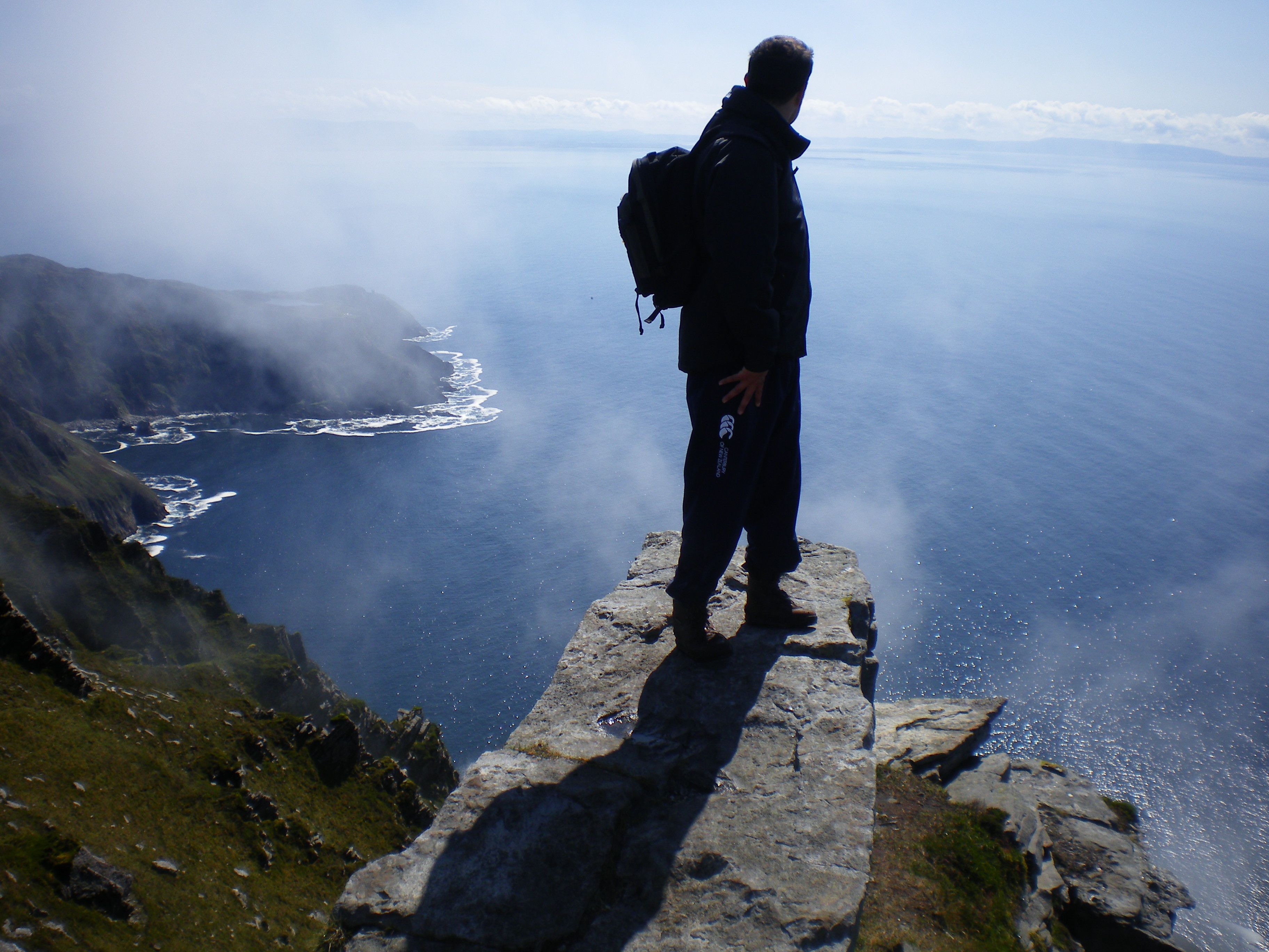 Siúlóir ag amharc amach ar an fharraige ó bharr Shliabh Liag